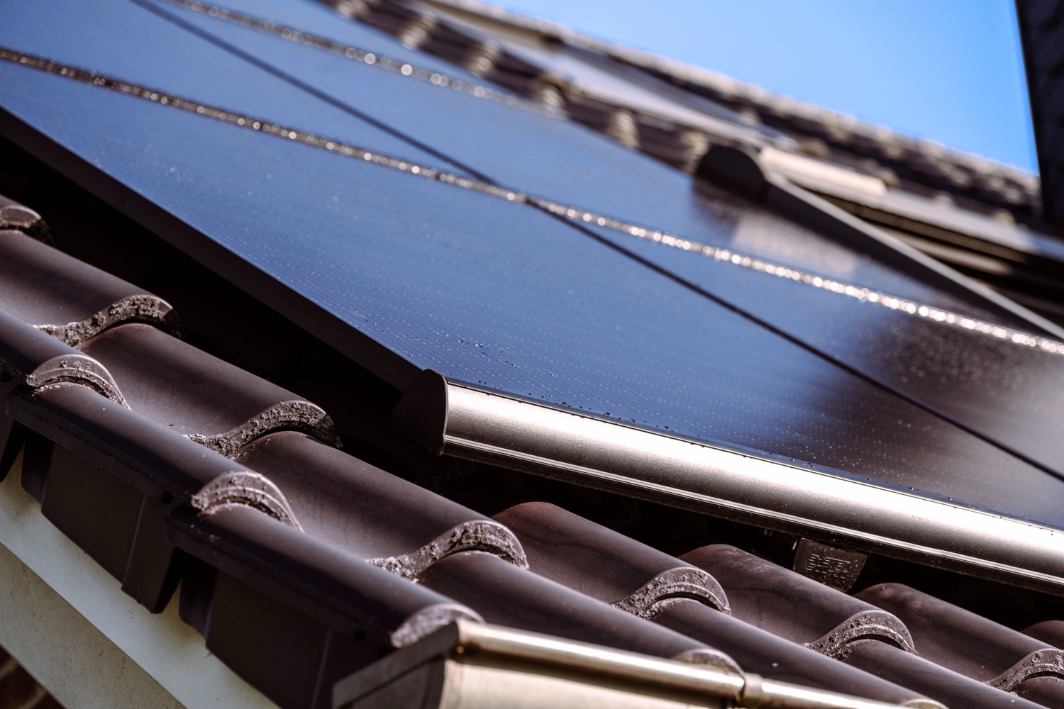 Schwarzes Photovoltaik-Modul auf einem Ziegeldach im Detail